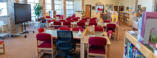 A bright school library filled with many chairs and tables for students to study and read comfortably.